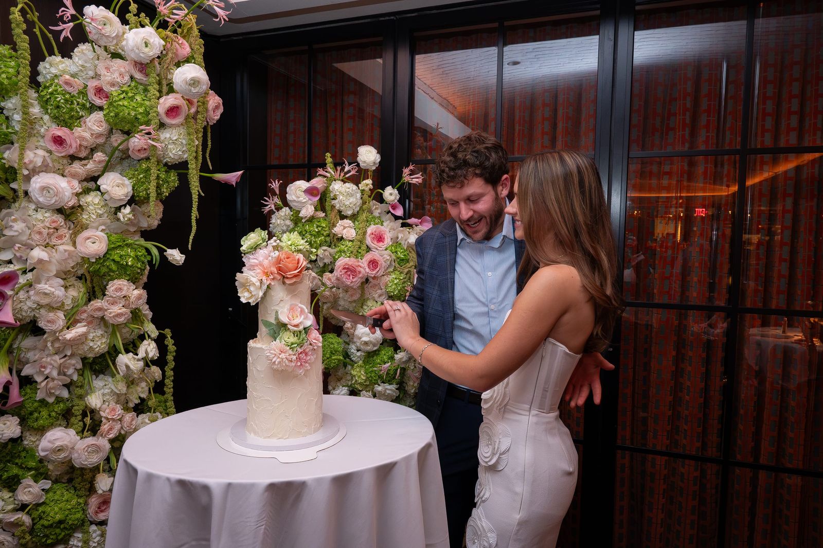 The engaged couple cutting their cake beside the floral installation.