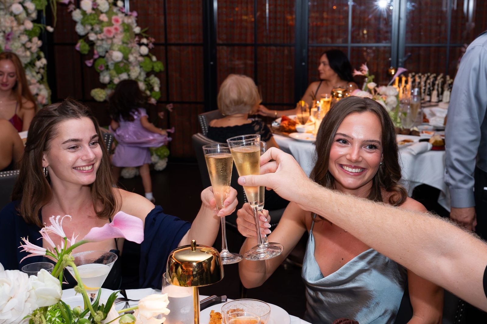 Two guests smiling as they raise their champagne flutes in a toast.