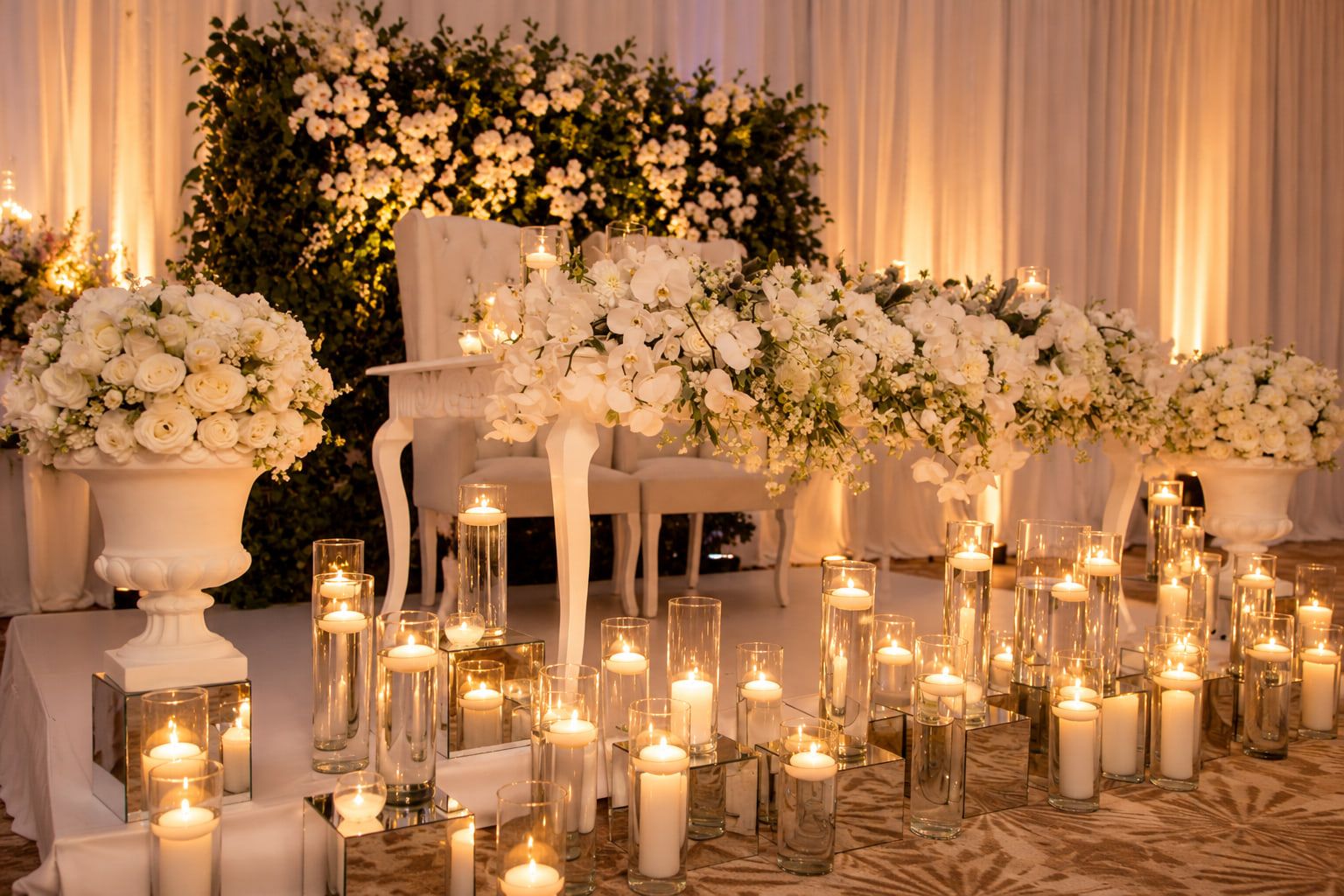 A sweetheart table draped in white orchids and roses, surrounded by floating candles.